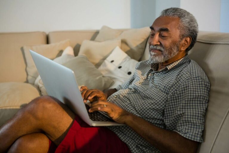 Proveer Senior Living | Senior man using laptop on couch