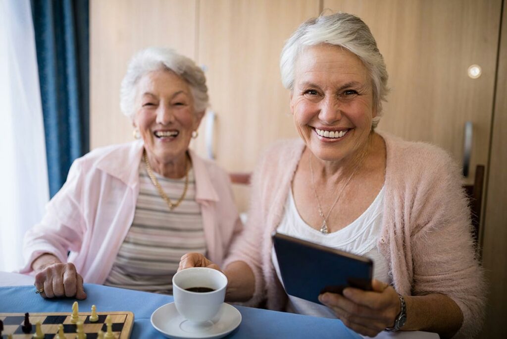 Proveer Senior Living | Senior Women Smiling With Tea & a Tablet
